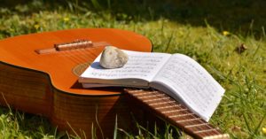 guitar and sheet music in grass